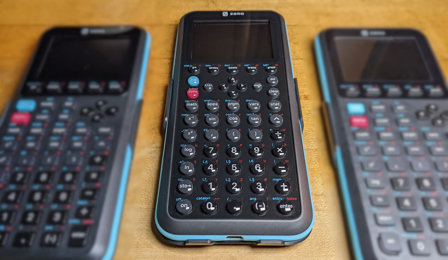 A photograph of three graphing calculators, the Zero Calculators ZGC3 in sharp focus at center, flanked by blurred ZGC1 and ZGC2 prototypes at left and right, respectively.